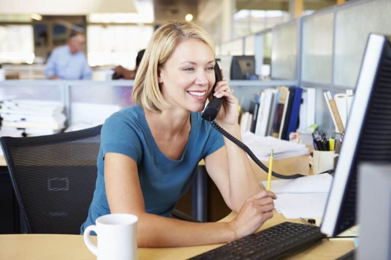 Young female employee talking on phone at office